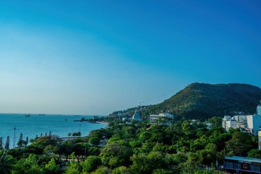 Vung Tau city aerial view with beautiful sunset and so many boats. Panoramic coastal Vung Tau view from above, with waves, coastline, streets, coconut trees and Tao Phung mountain in Vietnam.