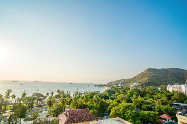 Vung Tau city aerial view with beautiful sunset and so many boats. Panoramic coastal Vung Tau view from above, with waves, coastline, streets, coconut trees and Tao Phung mountain in Vietnam.