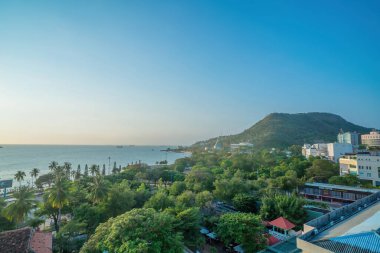 Vung Tau city aerial view with beautiful sunset and so many boats. Panoramic coastal Vung Tau view from above, with waves, coastline, streets, coconut trees and Tao Phung mountain in Vietnam.
