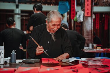 Vung Tau, Vietnam JAN 23 2022: Vietnamese scholar writes calligraphy at Long Son. Calligraphy festival is a popular tradition during Tet holiday. Writing couplets for Spring Festival at Luna new year