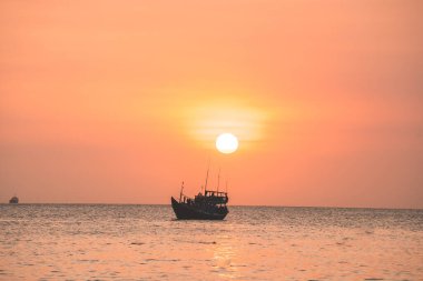 Tropical Seascape with a boat on sandy beach at cloudy sunrise or sunset. Beautiful sunset tropical beach with small boat and cinematic sky for travel and vacation in holiday relax time.