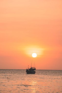 Tropical Seascape with a boat on sandy beach at cloudy sunrise or sunset. Beautiful sunset tropical beach with small boat and cinematic sky for travel and vacation in holiday relax time.