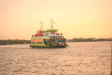 HO CHI MINH, VIETNAM - FEB 19 2022: A ferry brings commuters and vehicles from Cat Lai New Port to the opposite bank of the Nha Be River. Ho Chi Minh City is the largest city in Vietnam (9 mln)