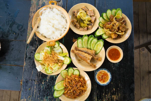 Vietnam family home cook set for four person: cooked rice, vegetable soup and fried fishes, fried onions with chicken, cucumber slice, Vietnamese Traditional Meal in Country side.