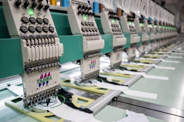 Modern and automatic high technology sewing machine for textile or clothing apparel making manufacturing process in industrial. Digital textile industry. Computerized embroidery.