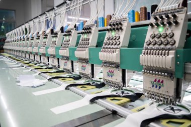 Modern and automatic high technology sewing machine for textile or clothing apparel making manufacturing process in industrial. Digital textile industry. Computerized embroidery.