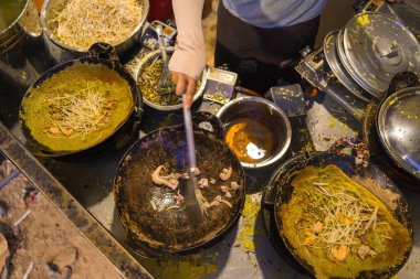 Vietnamese Banh Xeo crepes filled with pork or chicken may also, shrimp, onions and bean sprouts, and hot sauce placed near the plate on the table