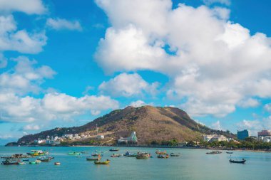 Vung Tau city aerial view with beautiful sunset and so many boats. Panoramic coastal Vung Tau view from above, with waves, coastline, streets, coconut trees and Tao Phung mountain in Vietnam.