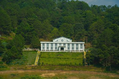 Focus white house at Tuyen Lam lake at Dalat, Vietnam, beautiful landscape for eco travel at Viet Nam, amazing lake among pine forest make wonderful scene, boat on water,