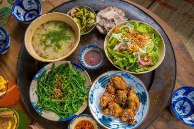 Vietnam family home cook set for four person: cooked rice, vegetable soup and fried fishes, fried onions with chicken, cucumber slice, Vietnamese Traditional Meal in Country side.