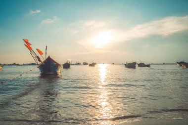 Tropical Seascape with a boat on sandy beach at cloudy sunrise or sunset. Beautiful sunset tropical beach with small boat and cinematic sky for travel and vacation in holiday relax time.
