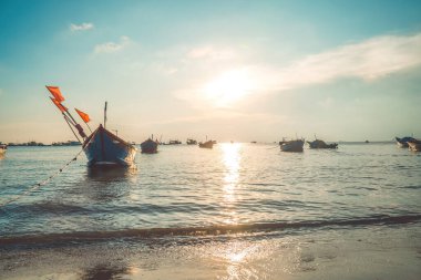 Tropical Seascape with a boat on sandy beach at cloudy sunrise or sunset. Beautiful sunset tropical beach with small boat and cinematic sky for travel and vacation in holiday relax time.