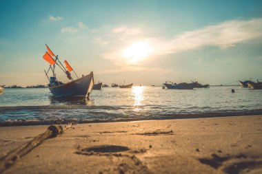 Tropical Seascape with a boat on sandy beach at cloudy sunrise or sunset. Beautiful sunset tropical beach with small boat and cinematic sky for travel and vacation in holiday relax time.