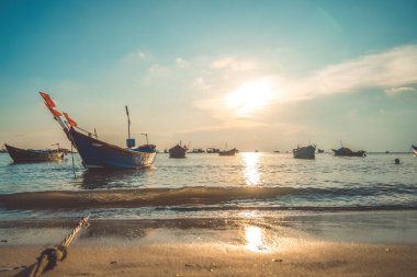 Tropical Seascape with a boat on sandy beach at cloudy sunrise or sunset. Beautiful sunset tropical beach with small boat and cinematic sky for travel and vacation in holiday relax time.