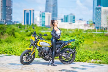 Ho Chi Minh, VIETNAM - MAY 22 2022: Focus young sexy model girl smiles and riding, posing a new model of Ducati motorcycle, at Thu Thiem peninsula