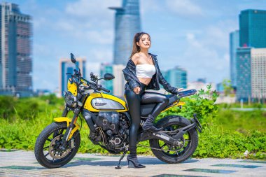 Ho Chi Minh, VIETNAM - MAY 22 2022: Focus young sexy model girl smiles and riding, posing a new model of Ducati motorcycle, at Thu Thiem peninsula