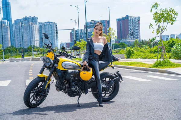 Ho Chi Minh, VIETNAM - MAY 22 2022: Focus young sexy model girl smiles and riding, posing a new model of Ducati motorcycle, at Thu Thiem peninsula