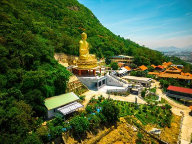 Ariel view Golden Buddha statue's hand holding lotus at Chon Khong Monastery which attracts tourists to visit spiritually on weekends in Vung Tau, Vietnam. Travel concept.