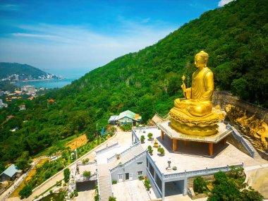 Ariel view Golden Buddha statue's hand holding lotus at Chon Khong Monastery which attracts tourists to visit spiritually on weekends in Vung Tau, Vietnam. Travel concept.