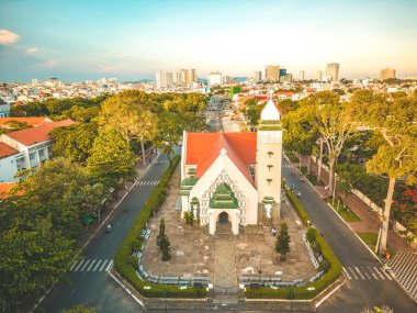Top view of Beautiful old church of Vung Tau city with green tree. Catholic temple village of Vung Tau, Vietnam. Photo of spring landscape with sunset.