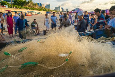 Vung Tau, VIETNAM - AUG 20 2022 : Fisherman casting his net at the sunrise or sunset. Traditional fishermen prepare the fishing net. Fishermen on beach at the Fishing.