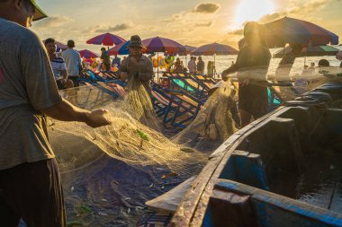 Vung Tau, VIETNAM - AUG 20 2022 : Fisherman casting his net at the sunrise or sunset. Traditional fishermen prepare the fishing net. Fishermen on beach at the Fishing.