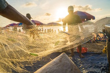 Vung Tau, VIETNAM - AUG 20 2022 : Fisherman casting his net at the sunrise or sunset. Traditional fishermen prepare the fishing net. Fishermen on beach at the Fishing.