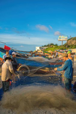 Vung Tau, VIETNAM - AUG 20 2022 : Fisherman casting his net at the sunrise or sunset. Traditional fishermen prepare the fishing net. Fishermen on beach at the Fishing.