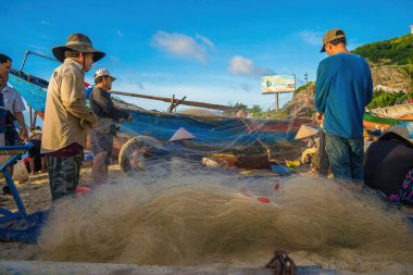 Vung Tau, VIETNAM - AUG 20 2022 : Fisherman casting his net at the sunrise or sunset. Traditional fishermen prepare the fishing net. Fishermen on beach at the Fishing.
