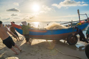 Vung Tau, VIETNAM - AUG 20 2022 : Fisherman casting his net at the sunrise or sunset. Traditional fishermen prepare the fishing net. Fishermen on beach at the Fishing.