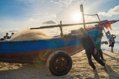 Vung Tau, VIETNAM - AUG 20 2022 : Fisherman casting his net at the sunrise or sunset. Traditional fishermen prepare the fishing net. Fishermen on beach at the Fishing.