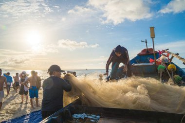 Vung Tau, VIETNAM - AUG 20 2022 : Fisherman casting his net at the sunrise or sunset. Traditional fishermen prepare the fishing net. Fishermen on beach at the Fishing.