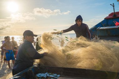 Vung Tau, VIETNAM - AUG 20 2022 : Fisherman casting his net at the sunrise or sunset. Traditional fishermen prepare the fishing net. Fishermen on beach at the Fishing.