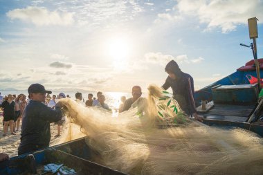 Vung Tau, VIETNAM - AUG 20 2022 : Fisherman casting his net at the sunrise or sunset. Traditional fishermen prepare the fishing net. Fishermen on beach at the Fishing.
