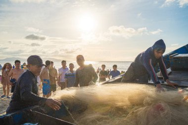 Vung Tau, VIETNAM - AUG 20 2022 : Fisherman casting his net at the sunrise or sunset. Traditional fishermen prepare the fishing net. Fishermen on beach at the Fishing.