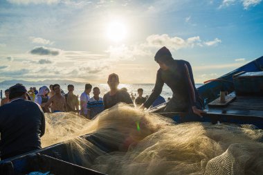 Vung Tau, VIETNAM - AUG 20 2022 : Fisherman casting his net at the sunrise or sunset. Traditional fishermen prepare the fishing net. Fishermen on beach at the Fishing.