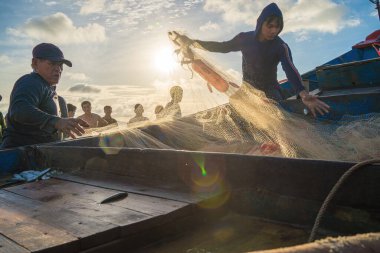 Vung Tau, VIETNAM - AUG 20 2022 : Fisherman casting his net at the sunrise or sunset. Traditional fishermen prepare the fishing net. Fishermen on beach at the Fishing.