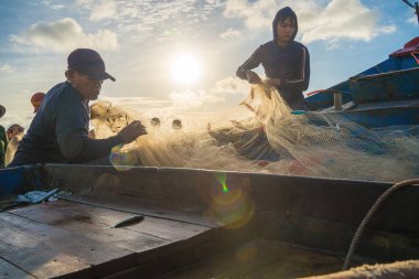Vung Tau, VIETNAM - AUG 20 2022 : Fisherman casting his net at the sunrise or sunset. Traditional fishermen prepare the fishing net. Fishermen on beach at the Fishing.