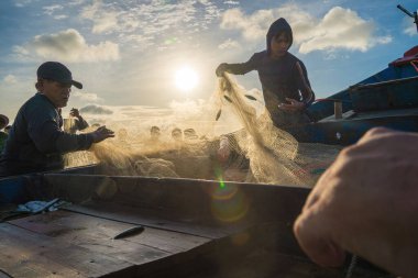 Vung Tau, VIETNAM - AUG 20 2022 : Fisherman casting his net at the sunrise or sunset. Traditional fishermen prepare the fishing net. Fishermen on beach at the Fishing.
