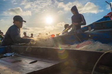 Vung Tau, VIETNAM - AUG 20 2022 : Fisherman casting his net at the sunrise or sunset. Traditional fishermen prepare the fishing net. Fishermen on beach at the Fishing.