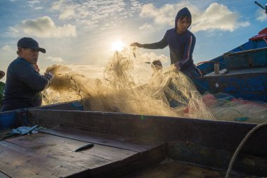 Vung Tau, VIETNAM - AUG 20 2022 : Fisherman casting his net at the sunrise or sunset. Traditional fishermen prepare the fishing net. Fishermen on beach at the Fishing.