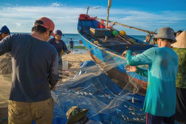 Vung Tau, VIETNAM - AUG 20 2022 : Fisherman casting his net at the sunrise or sunset. Traditional fishermen prepare the fishing net. Fishermen on beach at the Fishing.