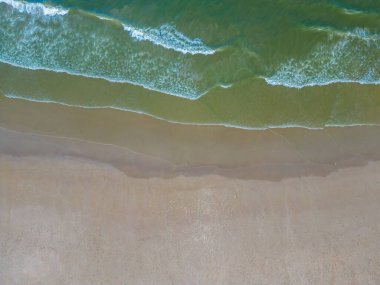 Havadan kumsal manzarası, yaz tatili şablonu afişi. Dalgalar inanılmaz mavi okyanus gölü, deniz kıyısı, kıyı şeridi ile sörf yapar. Mükemmel bir hava aracı üst görüntüsü. Huzurlu, parlak sahil, deniz kenarı.