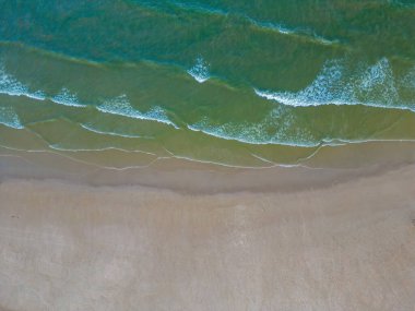 Havadan kumsal manzarası, yaz tatili şablonu afişi. Dalgalar inanılmaz mavi okyanus gölü, deniz kıyısı, kıyı şeridi ile sörf yapar. Mükemmel bir hava aracı üst görüntüsü. Huzurlu, parlak sahil, deniz kenarı.