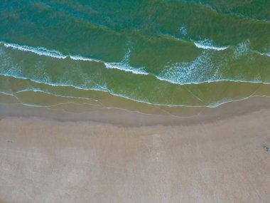 Havadan kumsal manzarası, yaz tatili şablonu afişi. Dalgalar inanılmaz mavi okyanus gölü, deniz kıyısı, kıyı şeridi ile sörf yapar. Mükemmel bir hava aracı üst görüntüsü. Huzurlu, parlak sahil, deniz kenarı.
