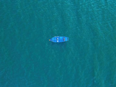 Top view, aerial view wooden fishing boat on the beach from a drone. Royalty high quality stock photo image of the wooden fishing boat on the beach. Fishing boat is mooring on clear blue beach alone