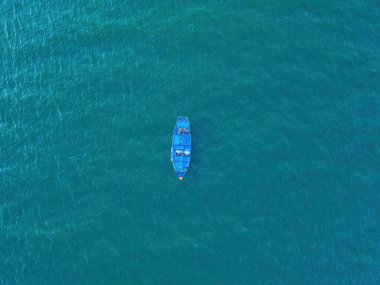 Top view, aerial view wooden fishing boat on the beach from a drone. Royalty high quality stock photo image of the wooden fishing boat on the beach. Fishing boat is mooring on clear blue beach alone