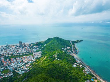 Vung Tau city aerial view with beautiful sunset and so many boats. Panoramic coastal Vung Tau view from above, with waves, coastline, streets, coconut trees and Tao Phung mountain in Vietnam.