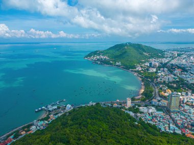 Vung Tau city aerial view with beautiful sunset and so many boats. Panoramic coastal Vung Tau view from above, with waves, coastline, streets, coconut trees and Tao Phung mountain in Vietnam.