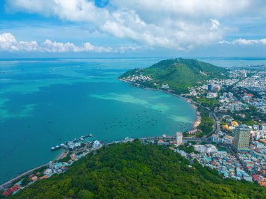 Vung Tau city aerial view with beautiful sunset and so many boats. Panoramic coastal Vung Tau view from above, with waves, coastline, streets, coconut trees and Tao Phung mountain in Vietnam.
